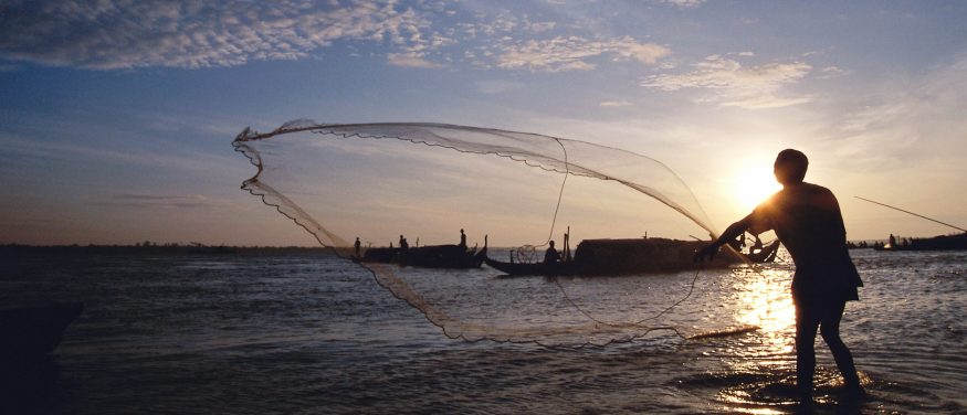 Fisherman casting a net over water